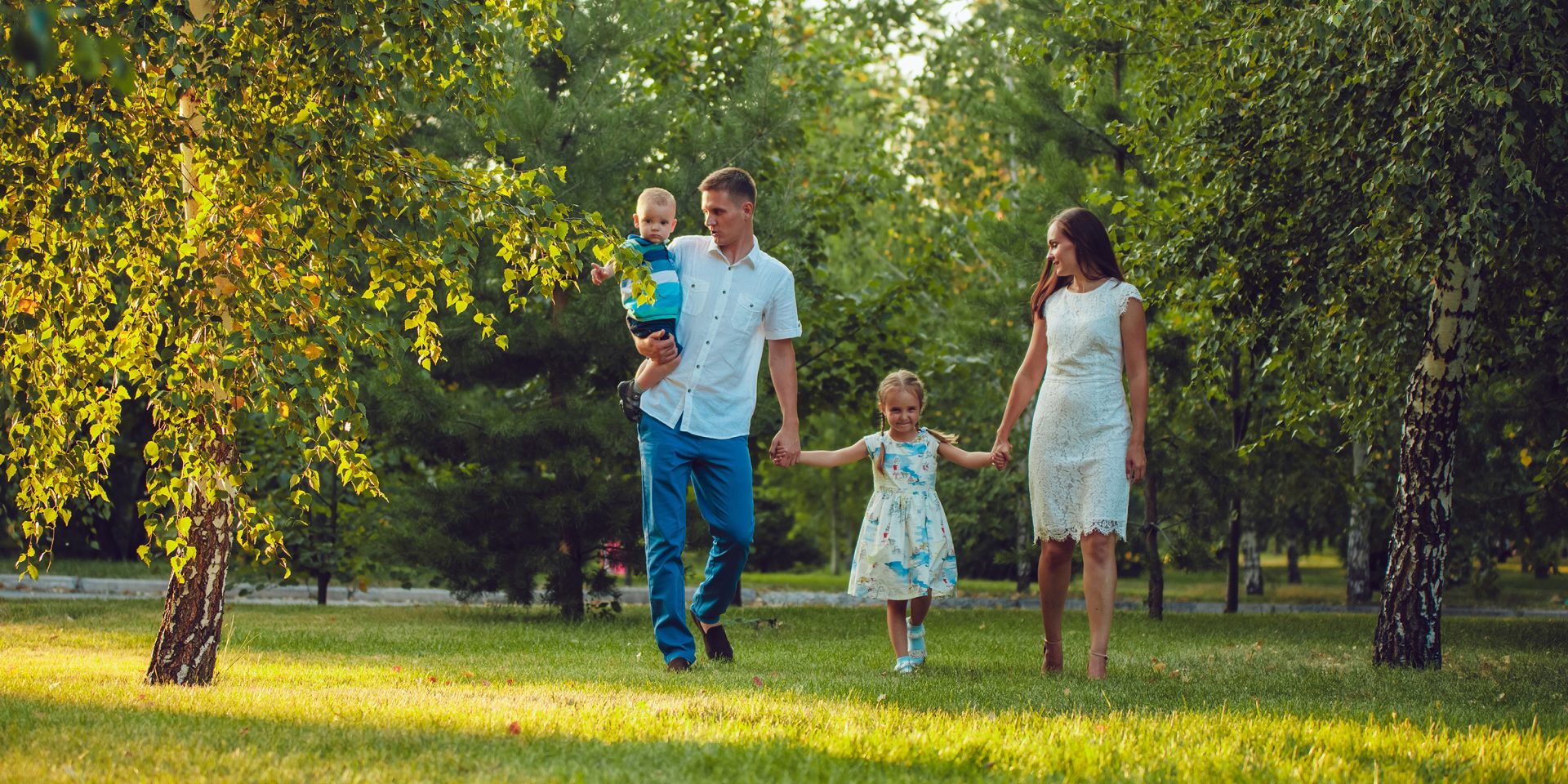Young family of four, walking amongst the trees