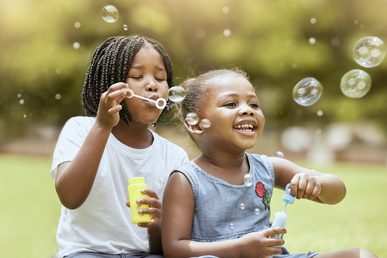 Two girls blowing bubbles outside